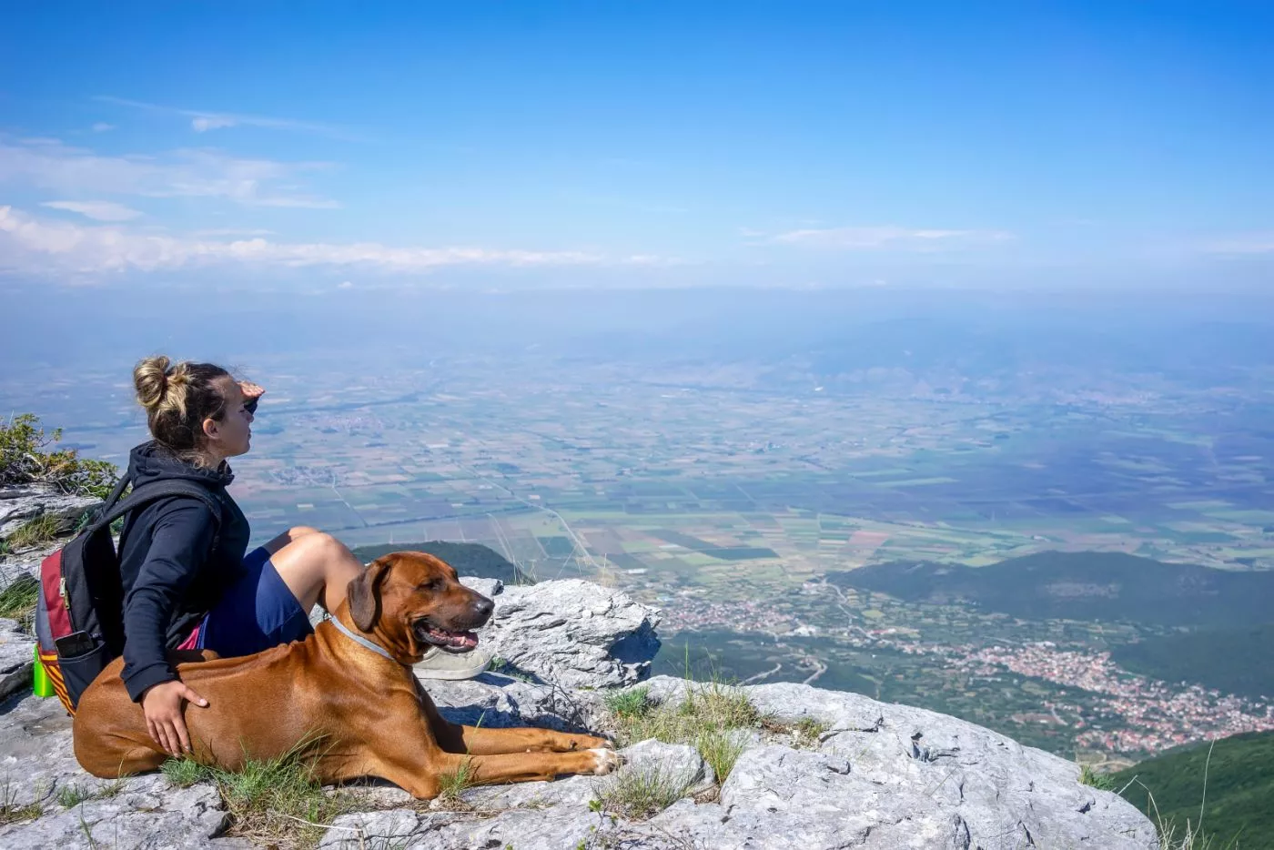 Djevojska sa rodezijskim goničem sjedi na planini